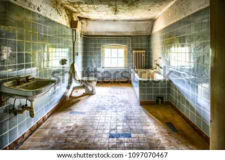 Renovated and very dirty bathroom with blue tiles in an old abandoned house
