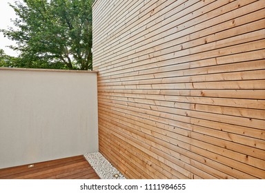 Renovated white ciment wall and insulating wood cladding in outdoor courtyard