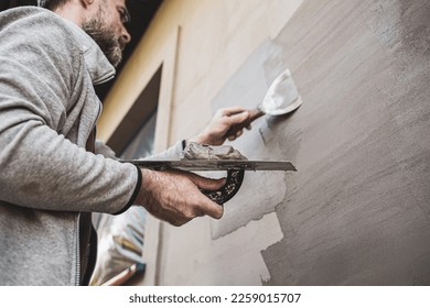 Renovation of the building facade - construction industry. Worker man (plasterer) plastering exterior walls of a house. - Shutterstock ID 2259015707
