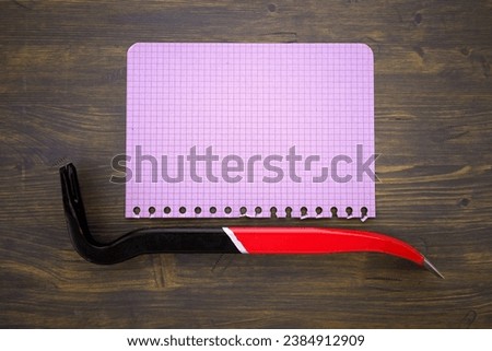 Renovation or construction concept with crowbar or wrecking bar on a memo notepad on wooden table and free copy space for text