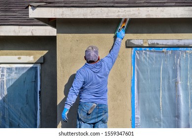 Renovation at home. construction worker putting decorative plaster on house exterior