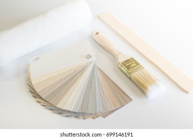 Renovation or home improvement items including a siding color sampler, paint brush, roller sleeve and stir stick on white