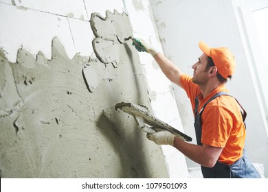 Renovation at home. Plasterer spreading plaster on wall.