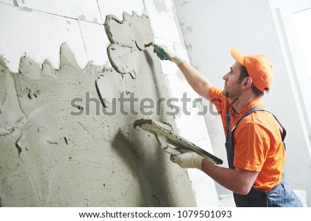 Renovation at home. Plasterer spreading plaster on wall.
