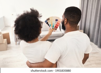 Renovation Planning. Black Family Couple Choosing Color For Walls Painting Holding Palette Standing Back To Camera At Home. House And Living Room Interior Design. Rear View, Selective Focus