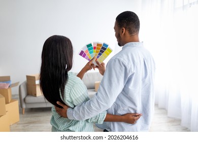 Renovation Planning. Young Black Couple Choosing Color For Walls Painting, Holding Palette, Standing In New Apartment, Back View. House And Living Room Interior Besign