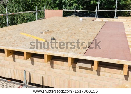 Renovation projects. Building of extension of the existing house, unfinished wooden roof structure, brick walls, view from scaffoliding, selective focus