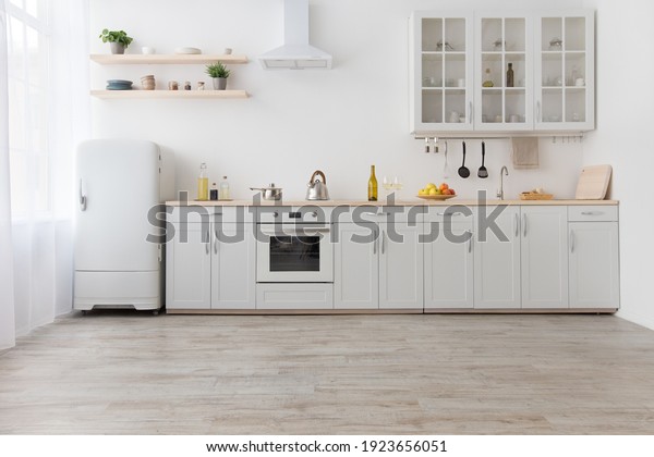 Rent of modern housing sale of new apartment,\
modern renovation. White furniture with utensils, shelves with\
crockery and plants in pots, refrigerator in simple minimal dining\
room, empty space