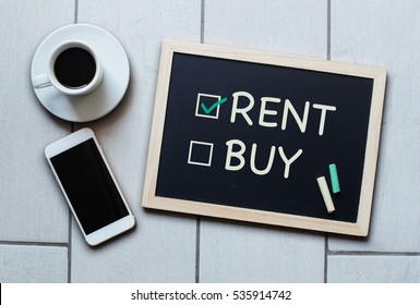 Rent Not Buy Blackboard Concept. Choosing Renting Over Buying With Coffee And Mobile Phone