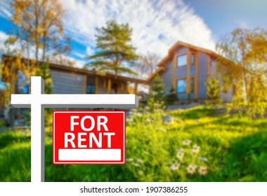 For Rent Sign Next To A Large House. For Rent Sign As A Symbol Of Private Property Renting. For Rent Sign On A Red Background. Concept - Rental A Private  House. Renting A Country House.