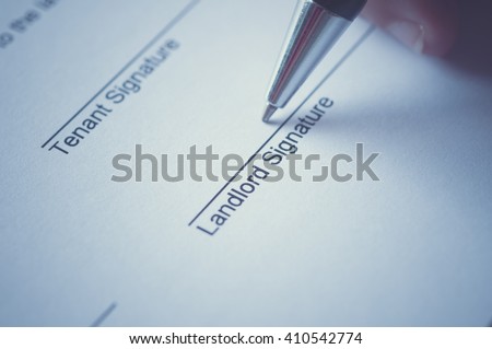 Rental agreement form with signing hand and pen.