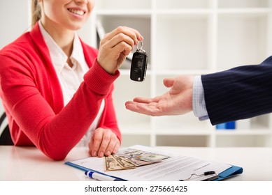 Rental contract. Transport purchase. Woman automotive dealer offering car key to buyer. Shallow depth of field.