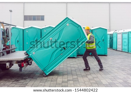 Rental lavatory being loaded on truck by worker