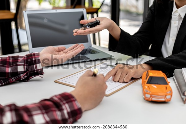 The renter is signing a car rental agreement with\
the car rental company. After discussing the details and charges\
with the employee, the employee hand over the car keys to the\
renter.