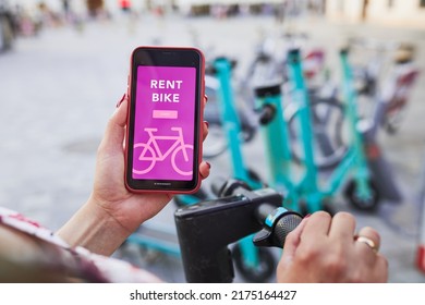 Renting bike using rental app on smartphone. Using bike sharing city service. Paid rent of electric scooter. Using mobile phone to rent and pay for public eco transport. Bike sharing city station