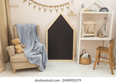 Renting children's room in eco-friendly cozy scandinavian style in beige style. Chair for reading fairy tales. Blank chalkboard mockup for notes. Open shelving with toys