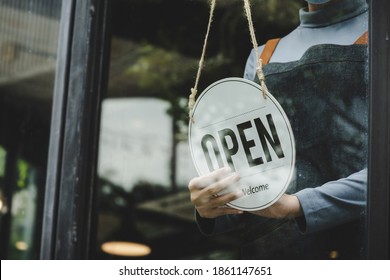 Reopen. Waitress Hand Wearing Protection Face Mask Turning Open Sign Board On Glass Door In Modern Cafe Coffee Shop, Cafe Restaurant, Retail Store, Small Business Owner, Food And Drink Concept