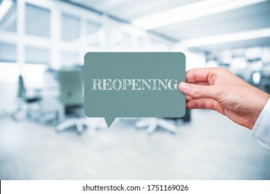 Reopening Office After End Of Covid-19 Quarantine Concept. Worker Hold Speech Bubble With Text Reopening, Office In Background.