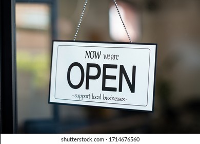 Reopening of a small business activity after the covid-19 emergency, ended the lockdown and quarantine. A business sign that says now we are open support local businesses hang on door at entrance. - Shutterstock ID 1714676560