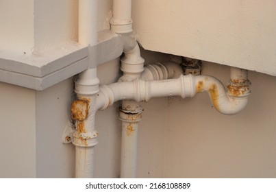 Repainted rustic pipes of drainage system from back of a building
