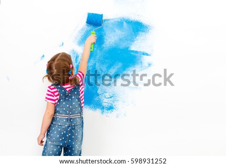 Repair in the apartment. Happy child girl paints the wall with blue paint