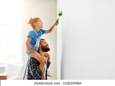 Repair In The Apartment. Happy Family Father And Child Daughter  Paints The Wall With Yellow Paint
