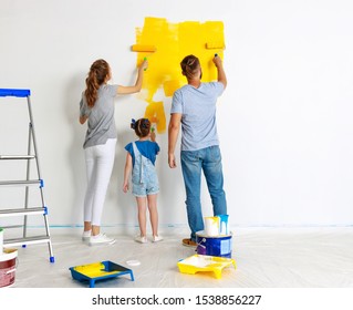 Repair In The Apartment. Happy Family Mother, Father  And Child Daughter    Paints The Wall With   Paint
