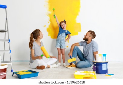 Repair In The Apartment. Happy Family Mother, Father  And Child Daughter    Paints The Wall With   Paint
