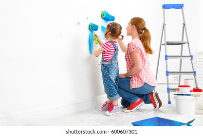 Repair In The Apartment. Happy Family Mother And Child Daughter  Paints The Wall With Blue Paint
