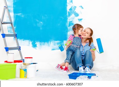 Repair In The Apartment. Happy Family Mother And Child Daughter  Paints The Wall With Blue Paint
