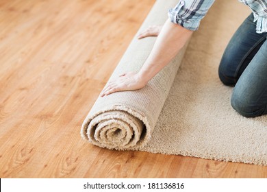 repair, building and home concept - close up of male hands unrolling carpet