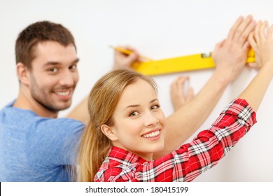 repair, building and home concept - smiling couple building new home using spirit level to measure - Powered by Shutterstock