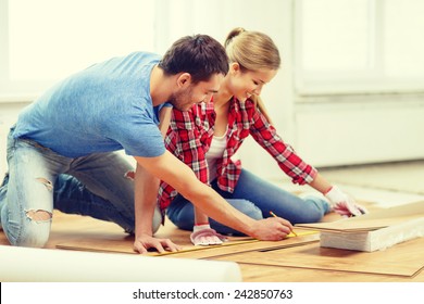 Repair, Building And Home Concept - Smiling Couple Measuring Wood Flooring