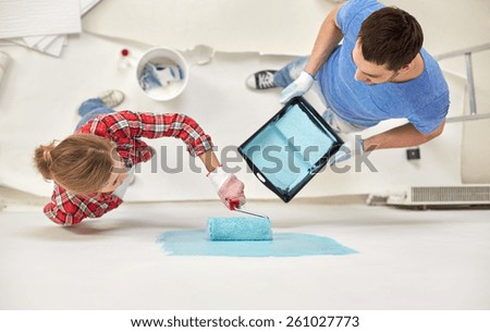 repair, building, people, teamwork and renovation concept - couple with paint and roller painting wall at home