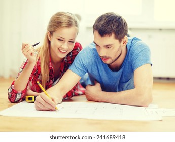 repair  building  renovation   home concept    smiling couple looking at blueprint at home