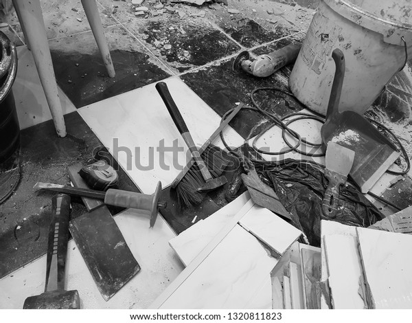 Repair building\
with tools and hammer, chisel, cleaver, brush, dustpan and tape\
measure on the floor with old\
tiles