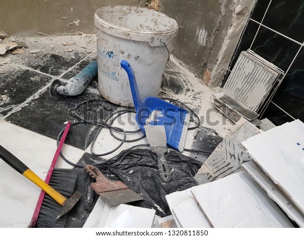 Repair building\
with tools and hammer, chisel, cleaver, brush, dustpan and tape\
measure on the floor with old\
tiles