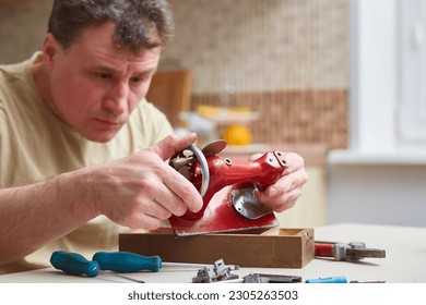 Repair of children's toy sewing machine. Focus on the typewriter. Male master repairs the sewing machine. Inspection of the mechanism in search of a breakdown. - Powered by Shutterstock