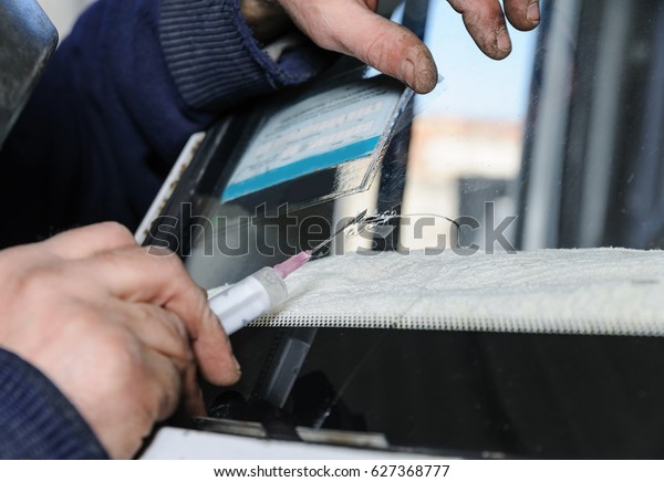 Repair cracked windshield. Fitter uses a\
syringe for applying the\
adhesive.