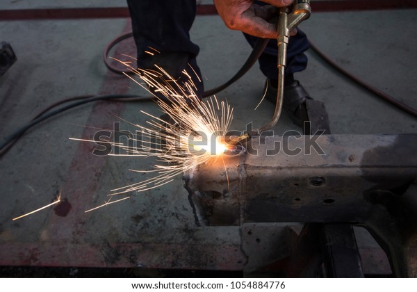 Repair of damaged car by\
accident in garage, using a gas fire to blow the hot iron, Before\
use a hammer to knock it back. Claim the insurance company. image\
style blur focus.