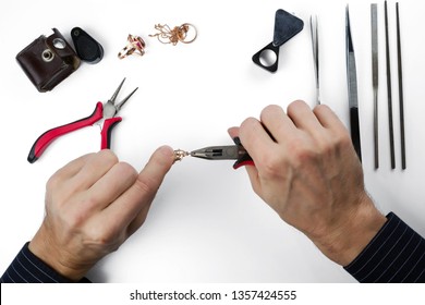 Repair Of Gold Jewelry. Hands Of The Jeweler With Tools And Jewellery Isolated On White Background.