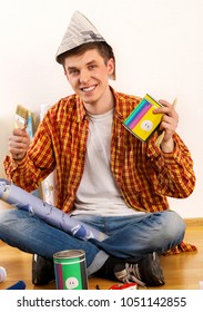 Repair Home Man Holding Paint Roller For Wallpaper. Tired And Frustrated Mad Male In Newspaper Cap Renovation Apartment. Paint Bank And Paint Brush In Hand. Loan For Housing For Students.