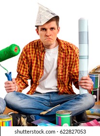 Repair Home Man Holding Paint Roller For Wallpaper. Tired And Frustrated Male In Newspaper Cap Renovation Apartment. Paint Bank And Roll Paper Background On Isolated.