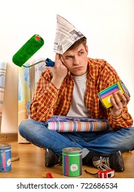 Repair Home Man Holding Paint Roller For Wallpaper. Tired And Frustrated Male In Newspaper Cap Renovation Apartment. Student Is Tired Of Moonlighting At Construction Site.