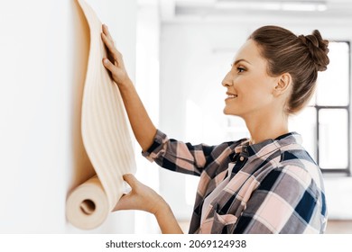 Repair, Improvement And Renovation Concept - Happy Smiling Woman Applying Wallpaper To Wall At Home