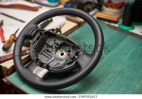 \
Repair of a\
leather car steering wheel in an auto repair shop on an old table.\
\
Disassembling the steering\
wheel