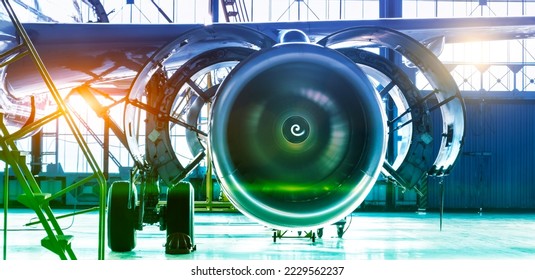 Repair maintenance of aircraft engine open hood on the wing of the plane. Industrial theme view in blue-green hue with bright sources of warm light. Format banner header wide size, place sample text - Powered by Shutterstock