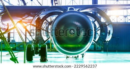 Repair maintenance of aircraft engine open hood on the wing of the plane. Industrial theme view in blue-green hue with bright sources of warm light. Format banner header wide size, place sample text