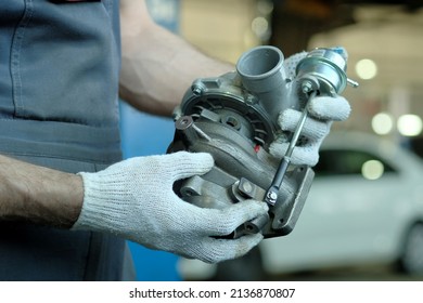 Repair and maintenance of the car. A new turbocharger is in the hands of an auto mechanic. Inspection of the spare part for compliance and integrity.
