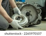 Repair and maintenance in a car service. Automatic transmission of a passenger car. An auto mechanic performs work on installing a torque converter.
